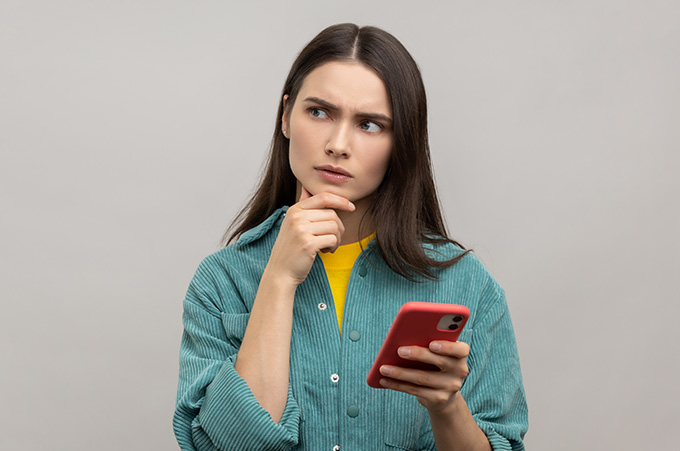 Mujer con expresin de duda y smartphone en su mano izquierda